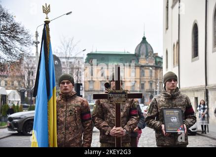 Lviv, Ucraina, 14/11/2022, Un soldato regge un ritratto di Tseng Sheng-Guang, ucciso dalle truppe russe in Ucraina, durante una cerimonia di congedo. Tseng Sheng-Guang (12.09.1997-02.11.2022) è un nativo di Taiwan. Si è laureato alla Scuola superiore Szu Wei di Hualien City. Durante il 2017-2021, prestò servizio nelle forze armate della Repubblica di Cina. Ricevuto il grado militare di 'Corporal'. Con l'inizio dell'invasione su vasta scala della Federazione Russa sul territorio dell'Ucraina, si unì volontariamente alle file delle forze armate ucraine. Combatté contro gli invasori russi come parte Foto Stock