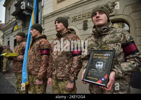 Lviv, Ucraina, 14/11/2022, Un soldato regge un ritratto di Tseng Sheng-Guang, ucciso dalle truppe russe in Ucraina, durante la cerimonia di congedo. Tseng Sheng-Guang (12.09.1997-02.11.2022) è un nativo di Taiwan. Si è laureato alla Scuola superiore Szu Wei di Hualien City. Durante il 2017-2021, prestò servizio nelle forze armate della Repubblica di Cina. Ricevuto il grado militare di 'Corporal'. Con l'inizio dell'invasione su vasta scala della Federazione Russa sul territorio dell'Ucraina, si unì volontariamente alle file delle forze armate ucraine. Combatté contro gli invasori russi come par Foto Stock