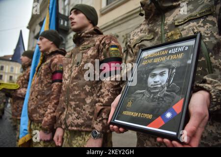 Lviv, Ucraina, 14/11/2022, Un soldato regge un ritratto di Tseng Sheng-Guang, ucciso dalle truppe russe in Ucraina, durante la cerimonia di congedo. Tseng Sheng-Guang (12.09.1997-02.11.2022) è un nativo di Taiwan. Si è laureato alla Scuola superiore Szu Wei di Hualien City. Durante il 2017-2021, prestò servizio nelle forze armate della Repubblica di Cina. Ricevuto il grado militare di 'Corporal'. Con l'inizio dell'invasione su vasta scala della Federazione Russa sul territorio dell'Ucraina, si unì volontariamente alle file delle forze armate ucraine. Combatté contro gli invasori russi come par Foto Stock