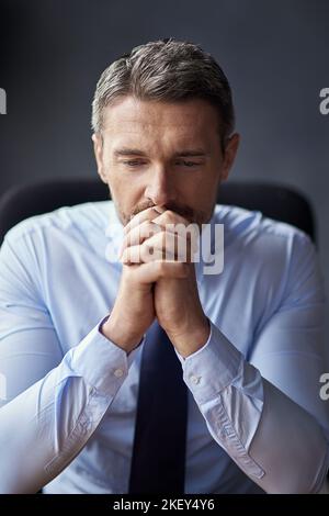 Lo stress sta arrivando a lui. Un uomo d'affari maturo che guarda ansioso mentre lavora nel suo ufficio. Foto Stock