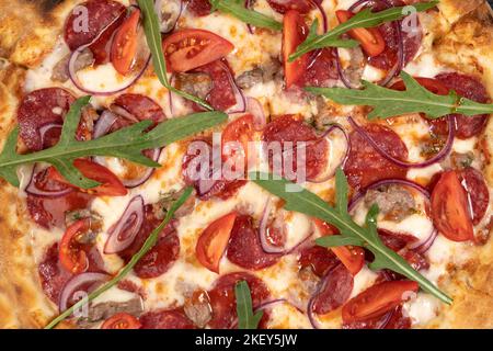 Pizza sfondo - macro shot di pizza con peperoni, salumi e rucola. Foto Stock