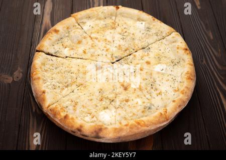 Pizza quattro formaggi fette su uno sfondo di legno. Pizza al formaggio Foto Stock