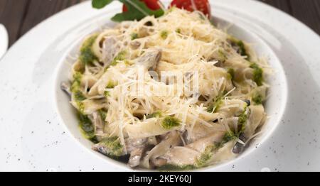 Piatto di pasta cremosa italiana con pollo e funghi decorato con salsa di basilico. Pranzo tradizionale italiano Foto Stock