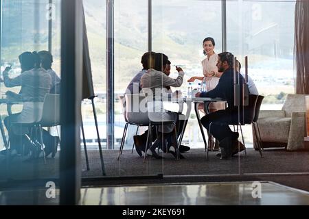 Sessione strategica in corso. Una donna d'affari che presenta un gruppo di colleghi in una sala riunioni. Foto Stock