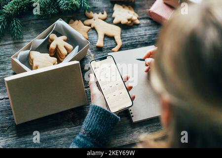 Donna irriconoscibile piani desideri per il 2023 nuovo anno tenendo un telefono con un calendario sullo schermo. Foto Stock