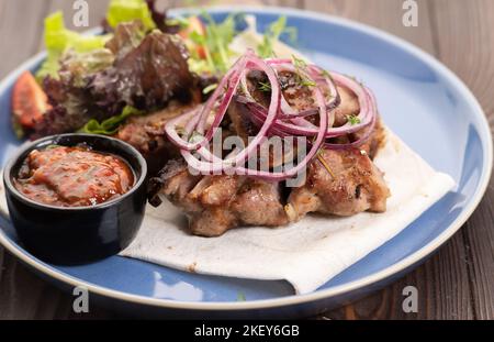 Kebab di maiale magro al barbecue serviti con lattuga fresca, cipolla e salsa di pomodoro, vista ravvicinata Foto Stock