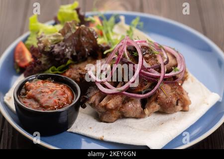 Sani kebab di maiale magri al barbecue serviti con lattuga fresca, cipolla e salsa di pomodoro, primo piano Foto Stock