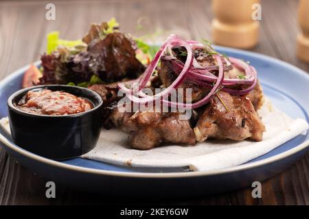 Piatto di maiale alla griglia con verdure fresche. Cibo foto di cubetti di maiale alla griglia con cipolla e lattuga. Carne gustosa con verdure cucinate nel ristorante Foto Stock