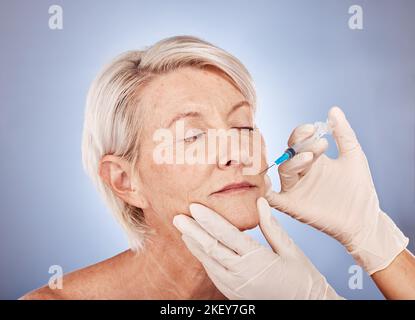 Botox, iniezione e donna anziana con mani di medico per la bellezza medica sullo sfondo grigio studio. Cura della pelle, benessere e pazienti anziani con Foto Stock