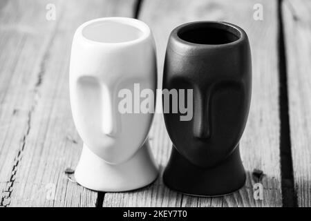 Scultura di due facce bianco e nero su un tavolo di legno, vaso di scultura, articoli per l'arredamento della casa Foto Stock