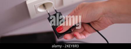 Donna mano che collega il caricabatterie del telefono cellulare al primo piano della presa Foto Stock