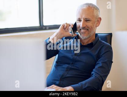 HES ha ottenuto l'etichetta telefonica impeccabile. Un uomo d'affari felice che risponde al suo telefono mentre lavora al suo computer in ufficio. Foto Stock