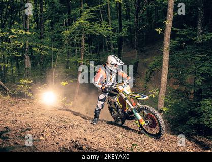 Cavaliere estremo arrampicata collina rocciosa nella foresta su fuoristrada motociclo enduro. Foto Stock