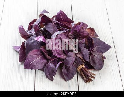 Foglie di basilico viola fresco su sfondo bianco di legno Foto Stock