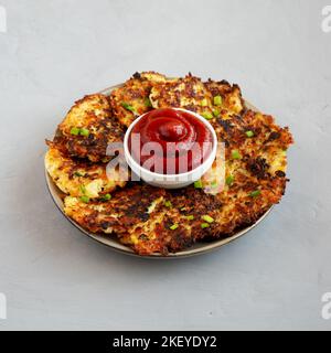 Cavolfiore casereccio Cheddar Fritters con erba cipollina su un piatto, vista laterale. Foto Stock