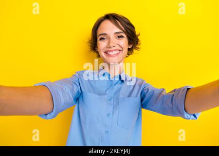 Selfie foto di giovane adorabile donna positiva indossare camicia blu toothy sorriso video registrazione riprese cadre ritratto isolato su colore giallo brillante Foto Stock