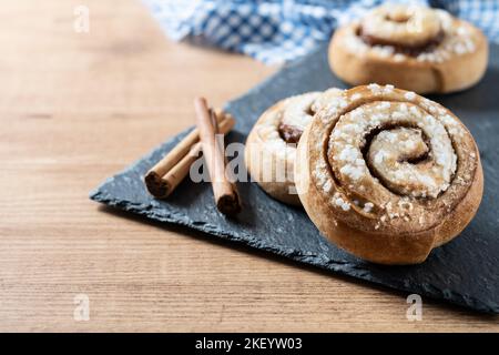 Panini alla cannella su tavolo di legno. Dessert svedese Kanelbule Foto Stock