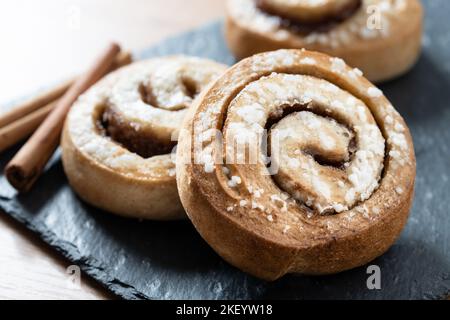 Panini alla cannella su tavolo di legno. Dessert svedese Kanelbule Foto Stock