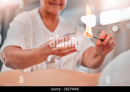 Donna, mani o fiamma per la terapia di cupping in spa, salone di hotel o trattamento cinese olistico per il sollievo dal dolore, stress muscolare o lesioni. Zoom, massaggio Foto Stock