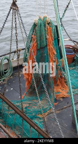 Colorate reti da pesca che si asciugano su un peschereccio a strascico nel porto di Whitby Foto Stock