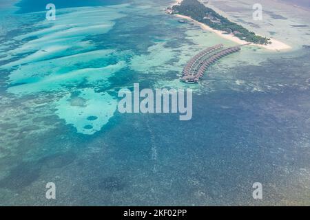 Maldive vista aerea paesaggio. Splendide ville sul mare blu e lussuose ville sull'acqua. Idrovolante vista aerea dell'atollo delle Maldive e della barriera corallina Foto Stock