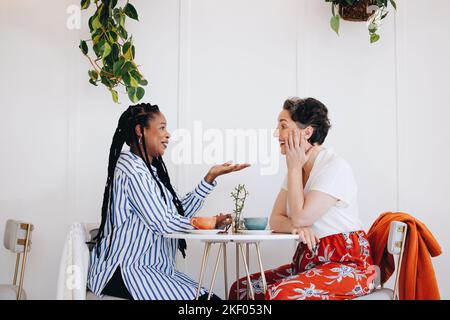 Colleghi donne felici che hanno una conversazione amichevole sopra il caffè in un caffè. Due donne d'affari allegre che hanno una pausa caffè chatty in un lavoro moderno Foto Stock