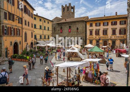 Bancarelle di mercato in Piazza Luca Signorelli con Chiesa evangelica 'i Fratelli' sullo sfondo nella cittadina collinare di Cortona in Toscana Foto Stock