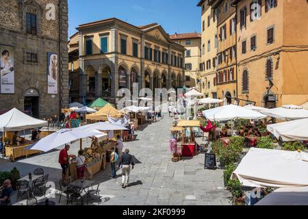 Bancarelle in Piazza Luca Signorelli con il Teatro Signorelli sullo sfondo nella cittadina collinare di Cortona in Toscana Foto Stock