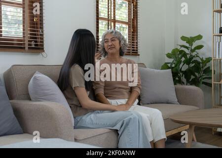 Figlia adulta che ama abbracciare la madre più anziana sul divano a casa, la famiglia godendo tenero momento insieme, giovane donna e madre matura o nonna in cerca Foto Stock