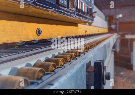 Primo piano di una parte della parte in legno su una macchina bordatrice. Macchina per la lavorazione del legno in un'officina di falegname Foto Stock