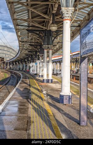 Una stazione ferroviaria dopo una pioggia. L'acqua si baglia sulla piattaforma e sulle rotaie. 19th ° secolo le tettoie sono sopra le piattaforme e un segno di benvenuto è Foto Stock