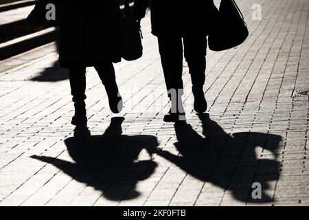 Silhouette e ombre di due donne che camminano lungo la strada della città. Concetto di amicizia femminile, società e popolazione Foto Stock