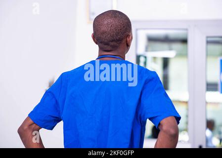 vista posteriore del giovane medico di sesso maschile che indossa uniforme blu in ospedale. Foto Stock