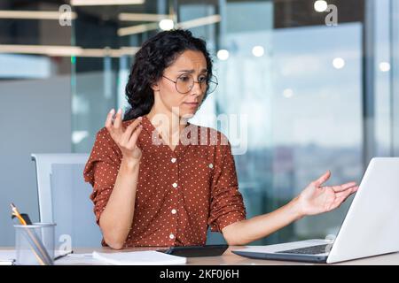 Donna d'affari delusa e triste al lavoro, non soddisfatto del risultato del risultato sul lavoro, donna ispanica disperata e triste che lavora in ufficio utilizzando il notebook al lavoro. Foto Stock