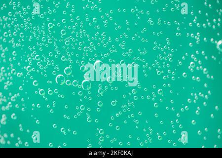 Gocce d'acqua sul vetro su sfondo verde. Macro artistica sotto la luce naturale, gocce d'aria su sfondo di vetro Foto Stock