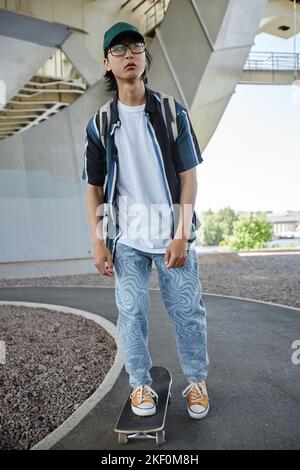 Ritratto completo di skateboard giovane asiatico in ambiente urbano Foto Stock