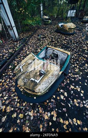 Abandoned Amusement Car Ride nella città fantasma di Pripyat nella zona di esclusione di Chernobyl, scooter nei colori autunnali Foto Stock