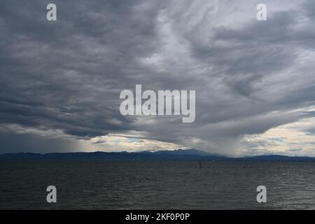 Pesanti nuvole di pioggia blu scuro e grigie sul lago di Costanza osservate dalla città tedesca Friedrichshafen. Foto Stock