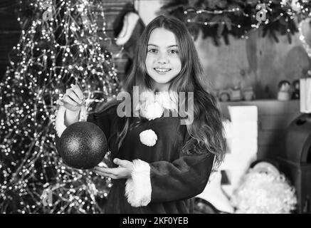 Servizi di noleggio decorazioni. Concetto di vacanze invernali. Festeggia l'anno nuovo vicino all'albero di natale. Noleggio costume da carnevale. Buona infanzia. Bambina Foto Stock