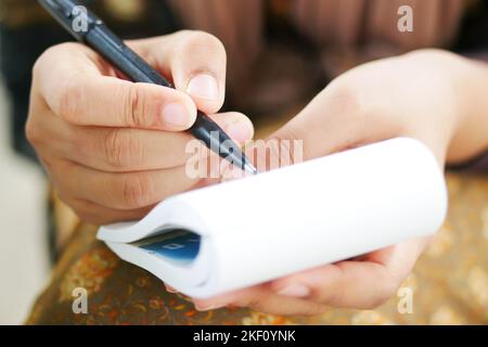 Primo piano di donne mano scrivere su blocco note. Foto Stock