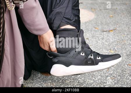 Primo piano sui piedi delle donne e massaggio delle mani sul punto di lesione. Foto Stock