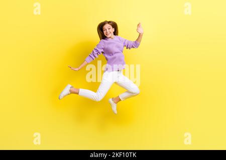 Foto a tutta lunghezza di donna overjoyed indossare alla moda viola maglia maglione buon umore fine settimana vacanza isolato su sfondo di colore giallo Foto Stock