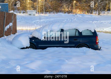 Auto coperta di spesso strato di neve di notte. Automobile dopo la tempesta di neve parcheggiata sul lato della strada. Foto Stock