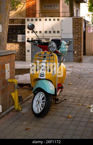 Uno scooter giallo brillante e colorato parcheggiato in centro Foto Stock