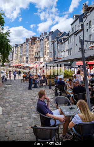 I contadini mangiano fuori nel porto di Honfleur, in Normandia, nell'estate calda 2022 - molti caffè e ristoranti di pesce. Foto Stock