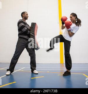 Studenti sportivi: Kickboxing. Una ragazza adolescente che impara le abilità di autodifesa sotto la supervisione del suo insegnante. Da una serie di immagini correlate. Foto Stock