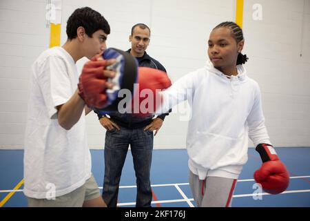 Studenti sportivi: Kickboxing. Ragazzi adolescenti che imparano le abilità di arti marziali sotto la supervisione del suo insegnante. Da una serie di immagini correlate. Foto Stock