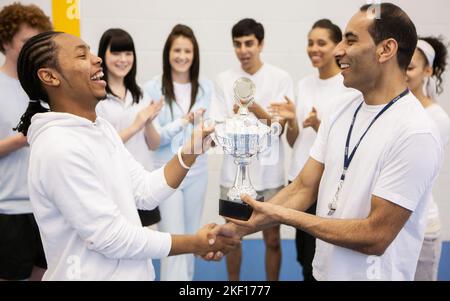 Studenti sportivi: Primo Premio. Una presentazione di trofei per uno sportivo adolescente con l'incoraggiamento della sua squadra. Da una serie di immagini correlate. Foto Stock