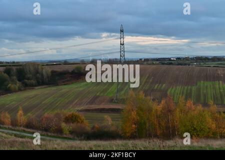 Royston, Barnsley, South Yorkshire, Regno Unito, 15th novembre 2022, Meteo. Pioggia pesante che puliva un crepuscolo sopra gli alberi nei colori autunnali, un pilone della griglia nazionale e turbine eoliche lontane. Paul Biggins/Alamy Live News Foto Stock