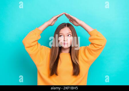 Foto di giovane divertente simpatico adolescente signora pensiero cercando spazio vuoto incerto scegliere nuovo appartamento mani tetto isolato su sfondo di colore ciano Foto Stock